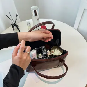 Brown leather cosmetic bag with top handle, portable makeup organizer and travel vanity case for women.