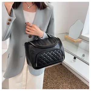 Detailed view of black leather travel cosmetic bag with quilted front pocket and zipper closure.
