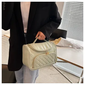 Detailed view of the elegant quilted cosmetic storage bag with top handle and gold zipper closure.