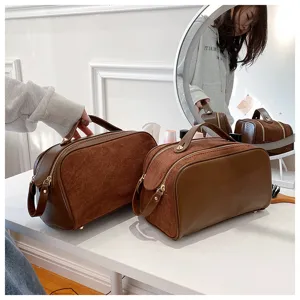 Brown cosmetic bag detail showcasing suede and leather texture with convenient top handle.