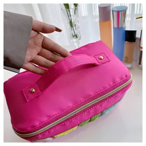 Nylon makeup bag detail view, showing the pink fabric texture, sturdy handle, and gold zipper.
