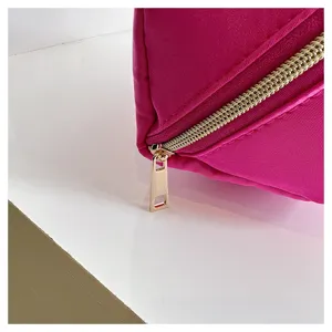 Close-up detail of hot pink nylon cosmetic bag with gold zipper and smooth texture.