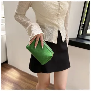 Detail view of the green woven cosmetic pouch, showcasing the soft leather texture and fine craftsmanship.