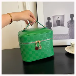Green PU leather cosmetic bag detail showing grid texture, dual zippers, and portable design.