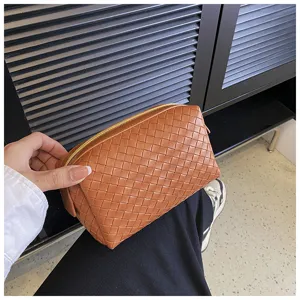 Brown woven leather cosmetic pouch detail, soft clutch bag texture close-up view