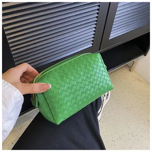 Detailed view of the green woven cosmetic bag, showing texture and portable design.