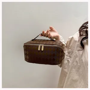 Brown quilted PU leather cosmetic bag detail view, portable makeup storage bag with handle.