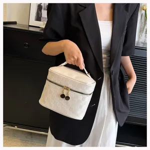 Close-up view of a stylish white grid pattern cosmetic bag held by a model in a blazer.
