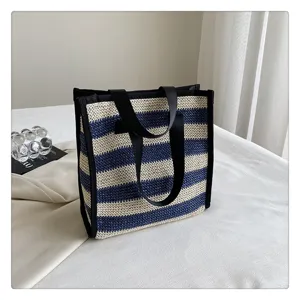 DETTAGLIO BORSA TRUCCO IN PAGLIA INTRECCIATA A RIGHE BLU E BIANCHE, BORSA SHOPPER CON MANICI NERI.