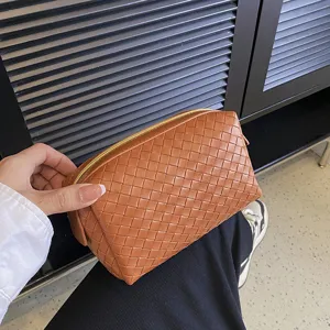 Brown woven leather cosmetic bag, portable travel makeup pouch, stylish handheld storage bag.