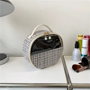 Round tweed cosmetic bag with portable handle and zipper closure for daily makeup storage.