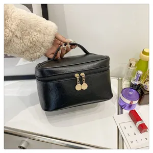 Black PU leather cosmetic bag with top handle and double zipper for travel makeup storage.
