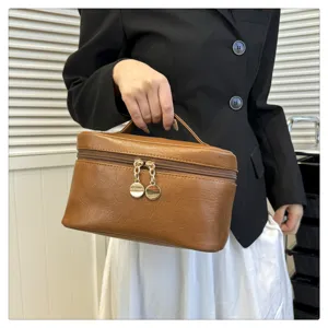 Detail view of a solid brown PU leather cosmetic bag with a portable handle and double zippers.