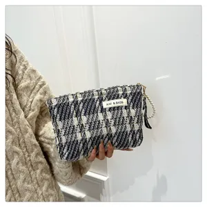 Elegant black and white tweed cosmetic pouch, chic handheld makeup bag with pearl strap.