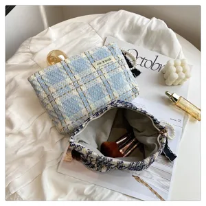 Detailed view of tweed plaid cosmetic bag with inner lining, elegant lifestyle makeup pouch detail.