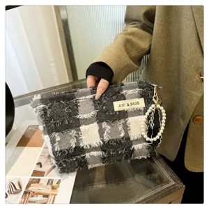 Black and white plaid cosmetic bag with pearl handle, trendy portable makeup pouch detail.