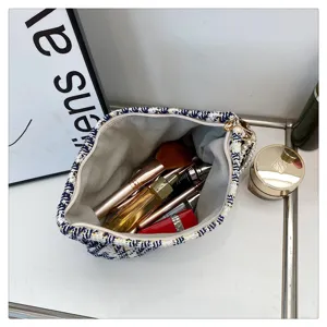 Chic tweed cosmetic bag featuring pearl strap, elegant makeup pouch for daily use.
