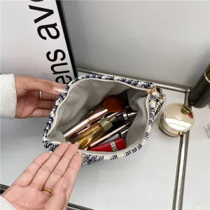 Tweed cosmetic bag open view with pearl strap and makeup brushes inside main image
