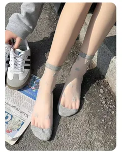 Nahaufnahme von transparenten Damen Glasesocken mit Sternenmuster, grauen Bündchen und Zehen.