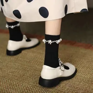Gros plan détaillé sur des chaussettes noires mignonnes ornées de perles et de chaussures.