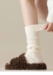 Close-up detail of knitted leg warmers in white, featuring ribbed texture and cozy warm style.