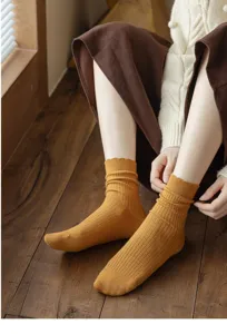 Close-up detail of cozy mustard yellow ribbed slouch socks worn indoors, soft knit texture.