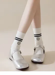 Close-up of women's white mid-calf socks featuring black stripes and smiley embroidery.
