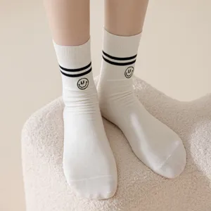 Comfortable white cotton crew socks featuring black double stripes and cute embroidered smiley face.