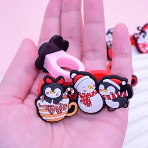 Gros plan sur les bagues PVC mignonnes de pingouin de Noël, détail de bijoux pour enfants.