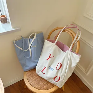 Canvas tote bag detail view, casual shoulder bag with letter embroidery and striped design.