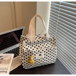 Detailed view of black white polka dot canvas tote bag with cute duck pendant and front label.