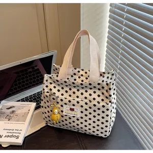Canvas tote bag detail showing black polka dot pattern, front pocket, and cute pendant design.