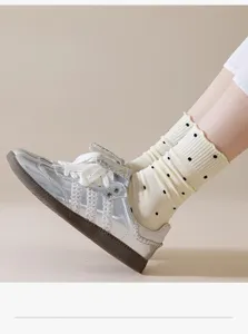 Women frilled polka dot mid-calf socks with stylish silver metallic casual sneakers.