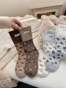 Detail shot of cozy autumn winter wool slouch socks with chic leopard print and cute cloth label.