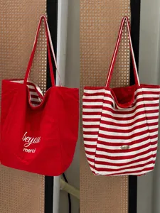 Detailed view of the red and white reversible canvas tote bag, showing striped and solid sides.