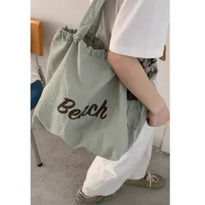 Detail view of the casual nylon tote bag with drawstring and Beach letter print design.