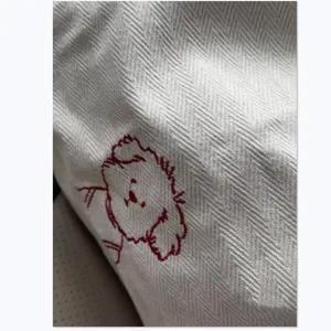 Close-up detail of canvas tote bag, featuring cute red puppy embroidery on white fabric.