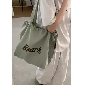 Close-up detail of the casual nylon tote bag showing the Beach letter embroidery and drawstring.