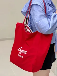 Detail view of the red canvas tote bag showing printed letters and striped lining interior.