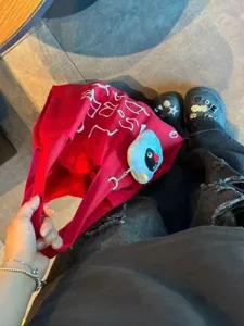 Red canvas tote bag detail view, casual large capacity shoulder bag with cute plush bird pendant.