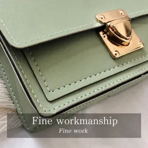 Detalle de bolso cuadrado pequeño de cuero PU verde claro con cierre metálico dorado y costuras.