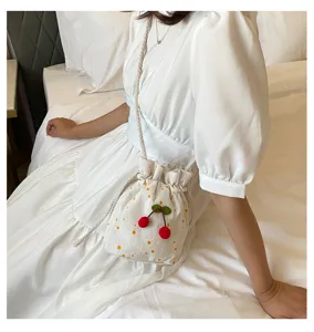 Vue détaillée de petit sac seau fleuri avec imprimé marguerite et pendentif cerise.