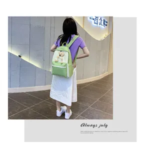 Green and white canvas school backpack for women with a cute bear pendant detail.