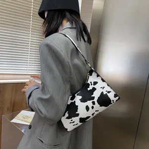 Detail shot of a chic black and white cow print shoulder bag, stylish mini baguette.