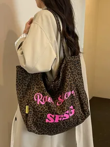 Vista dettagliata della borsa tote in tela leopardata vintage con eleganti lettere rosa.