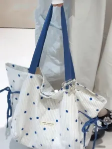 Detailed view of stylish blue polka dot canvas tote bag with contrast shoulder straps.