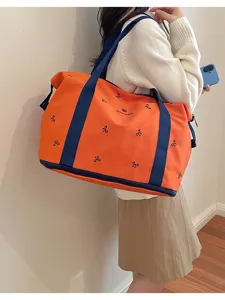 Orange travel duffel bag detail, blue straps and cute bow embroidery, large capacity gym accessory.