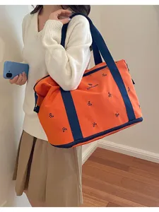 Women's orange travel duffel bag with bow embroidery and blue handles, casual daily storage.