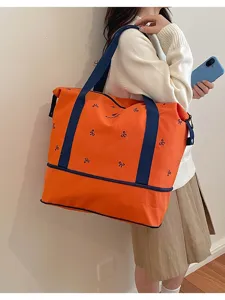Detail of the orange travel tote bag featuring blue handles and cute bow prints for stylish outings.