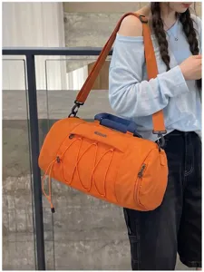 Close-up of the orange gym duffel bag showing front mesh pocket, blue handle, and adjustable strap.